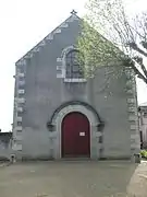 Photographie en couleurs de la façade d'un édifice religieux percée d'une porte surmontée d'une baie.