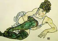 Portrait d'une femme allongée sur son coude gauche, jambes en bas verts repliées sur la poitrine, bras droit sous un genou