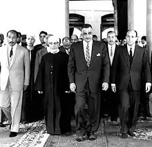 Photographie d'un groupe d'hommes en chaussettes marchant cote à cote sur un tapis.