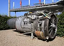 réacteur extrait de l'avion, exposé au sol. de nombreux tubes proéminents relient les parties du moteur entre elles.