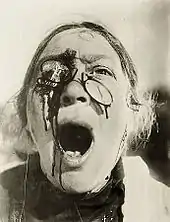 La tête d'une vieille femme criant avec les lunettes cassées et une blessure sanglante sur l'œil droit