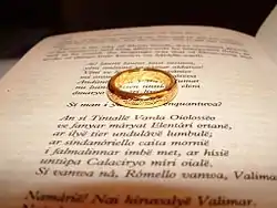 Photographie illustrative de l'univers du Seigneur des anneaux, montrant un anneau doré posé sur une page d'un livre ouvert.