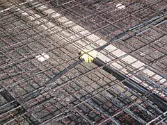 Installation horizontale des gaines souples de protection plastique du câblage sur treillis soudé avant coulage de dalle béton, après 1980.