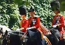 Élisabeth II en uniforme rouge sur un cheval noir