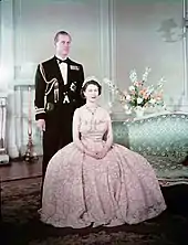 Photographie couleur d'une femme assise devant un homme en uniforme.