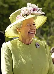 Photographie en plan taille de la Reine vêtue de jaune.