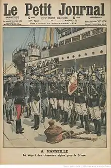 Soldats en rang sur un quai, devant un paquebot.
