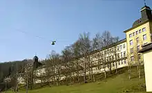 Long bâtiment de cinq étages dans un parc arboré.