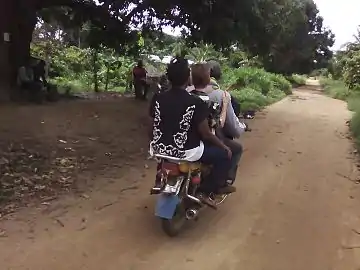 Sur la route départementale D47 Bafia-Ntui. Un mototaximan et ses deux passagers à Tsékané, allant à Boura 1.