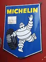 Photographie en couleurs d'une affiche représentant le bibendum Michelin poussant un pneu.