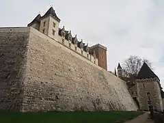 Photographie en couleurs d'un château surplombant un mur.