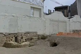 Base d'une tour de l'enceinte de Philippe Auguste, mise au jour lors des fouilles archéologiques dans l'Institut de France en 2015, avant la réalisation d'un nouveau bâtiment. L'enceinte marque la frontière entre l'Institut de France et la Monnaie de Paris. On voit également l'entrée d'un égout construit par Louis Le Vau dans les anciens fossés de l'enceinte, lors de la construction du Collège des Quatre-Nations au XVIIe siècle.