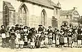 Enfants en costumes traditionnels bretons, devant l'église Saint-Budoc.