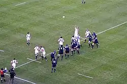 Photographie d'une touche dans un match de rugby à XV, entre l'équipe d'Angleterre en maillots blancs et l'équipe d'Écosse en maillots bleus