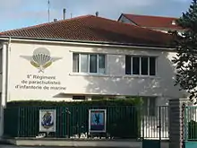 Photo couleur présentant un bâtiment orné du symbole des unités parachutistes et du titre su régiment.