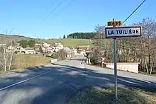 Panneau d'entrée d'agglomération et village de La Tuilière au second plan