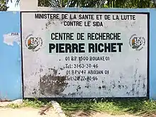 vue du mur à droite du portail d'entrée de l'institut montrant une peinture naïve, un peu délabrée, qui donne toutes les coordonnées de l'établissement