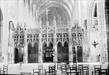  Photo noir et blanc montrant une séparation en pierre très découpée et sculptée barrant la nef d'un édifice religieux.