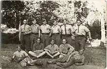 Photographie d'un groupe de soldats, en calot, chemise et cravate d'uniforme. Certains sont en short.