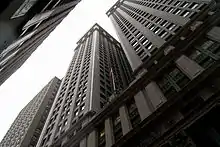 Photographie en contre-plongée d'un immeuble avec une très haute façade verticale laissant à peine voir le ciel.