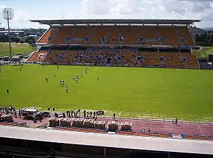 vue d'un stade depuis une tribune avec au premier plan une pelouse et au second-plan une tribune couvertes à deux étages