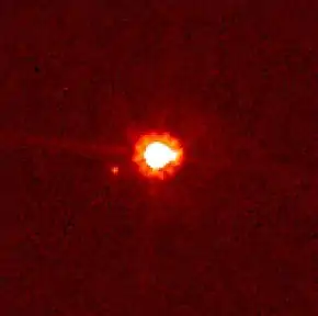 Image rougeâtre où un gros point blanc central au halo rouge est accompagné d'un autre plus petit.