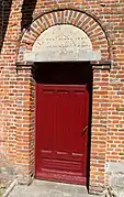 Porte latérale avec une imposte en pierre sculptée  "Sainte-Eugénie".