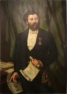 Portrait d'un homme décoré de la Légion d'honneur tenant à la main un rouleau de papier.