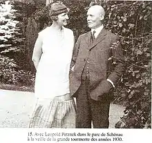 Photographie en noir et blanc d'un couple debout et se souriant : elle porte une tenue d'été claire, lui porte un costume sombre et a la tête dégarnie.