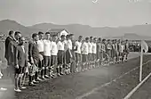 Photo en noir et blanc montrant des hommes alignés sur un terrain de football