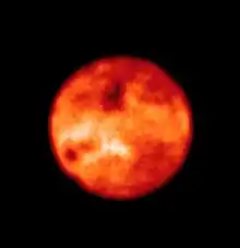 La lune est vue comme rouge avec des points sombres et blancs.