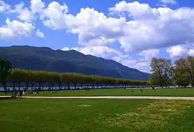 Photographie d'une pelouse publique, au bord d'un lac.