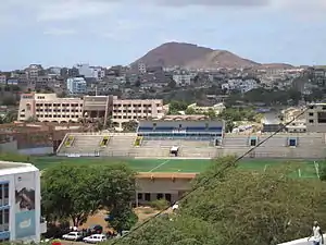 au premier plan, un stade, au second plan, des habitations et une montagne