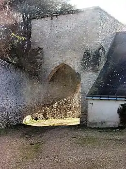 Photographie en couleurs d'une tour carrée percée d'un porche.