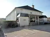 Photographie en couleurs d'un bâtiment moderne avec une large entrée vitére.