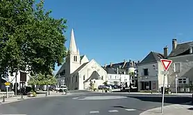 Photographie en couleurs d'un centre d'une commune avec une église en arrière-plan.