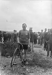 Photographie en noir et blanc d'un homme qui tient un vélo.