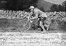 Photographie en noir et blanc d'un cycliste poussant son vélo.