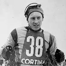 Photographie en noir et blanc d'un athlète portant un dossard marqué de l'inscription Cortina et du numéro 38.