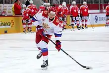 Photo couleur d’un hockeyeur, en pied, en train de faire un tir du poignet