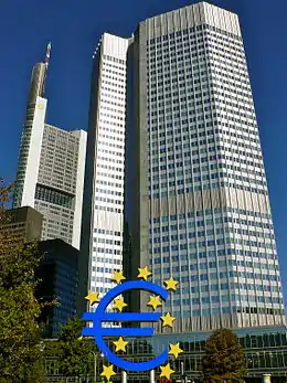 Gratte-ciel de l'Eurotower, 40 étages ; d'autres grattes-ciel plus petits sont visibles sur la gauche. En bas de la tour, une sculpture bleue du symbole de l'euro autour et dans lequel se trouvent onze étoiles jaune.