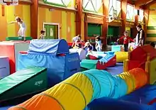 Photo couleur d'un gymnase rempli de matériel de gymnastique multicolore et d'enfants y jouant