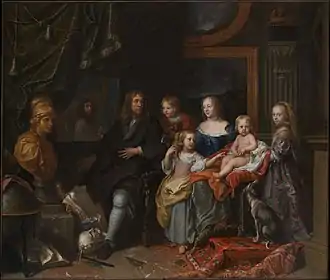 Portrait en pied d'un homme accompagné d'une femme et d'enfants dans un intérieur encombré d'œuvres d'art.