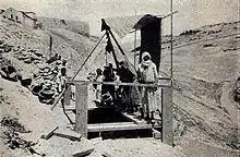 Photo noir et blanc de Palestiniens manœuvrant le treuil au-dessus du puits.