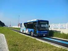 Vue d'un bus, suivant un marquage bleu, en descente.