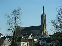 Photographie en couleurs prise au loin, l'église surplombant les maisons.