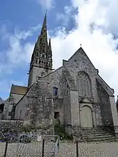 Photographie d'une façade d'église à deux niveaux, avec un portail de style classique surmonté d'une grande fenêtre de style gothique rayonnant