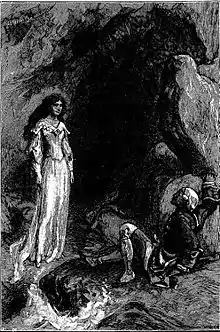 Une dame debout à l'entrée d'une grotte et un homme tombé face à elle.
