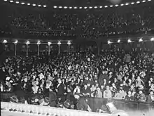 Photographie en noir et blanc de la grande salle du palais accueillant une foule pour la fête de Noël 1932.