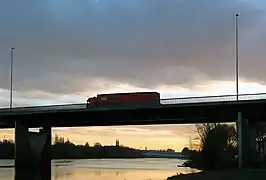 Passage d'un camion sur le viaduc de la Maine au soleil couchant ; en arrière-plan, la ville d'Angers.